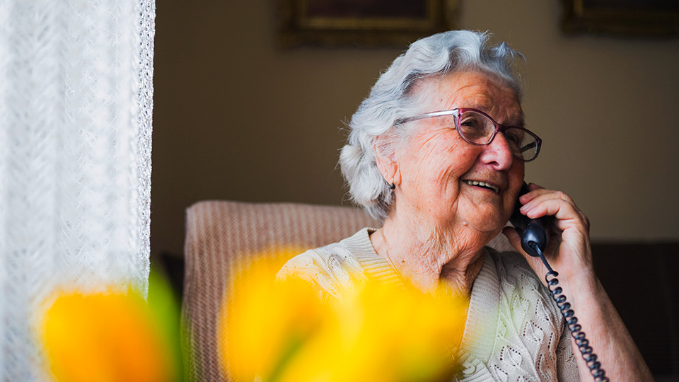 Foto de uma senhora de idade conversando pelo telefone.